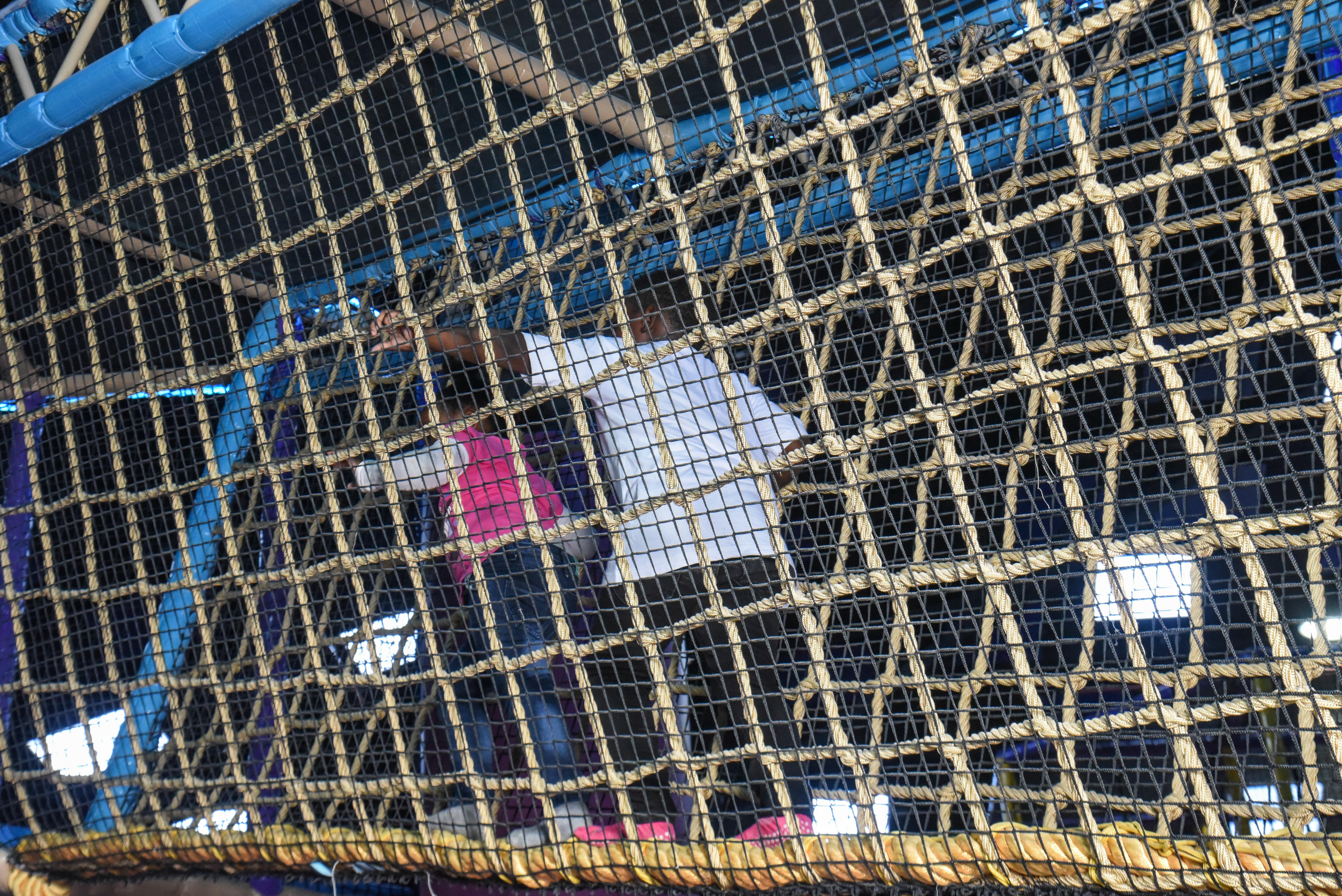 Child balancing in the net maze challenge at The Hub Park, a thrilling indoor fun zone and bounce place.