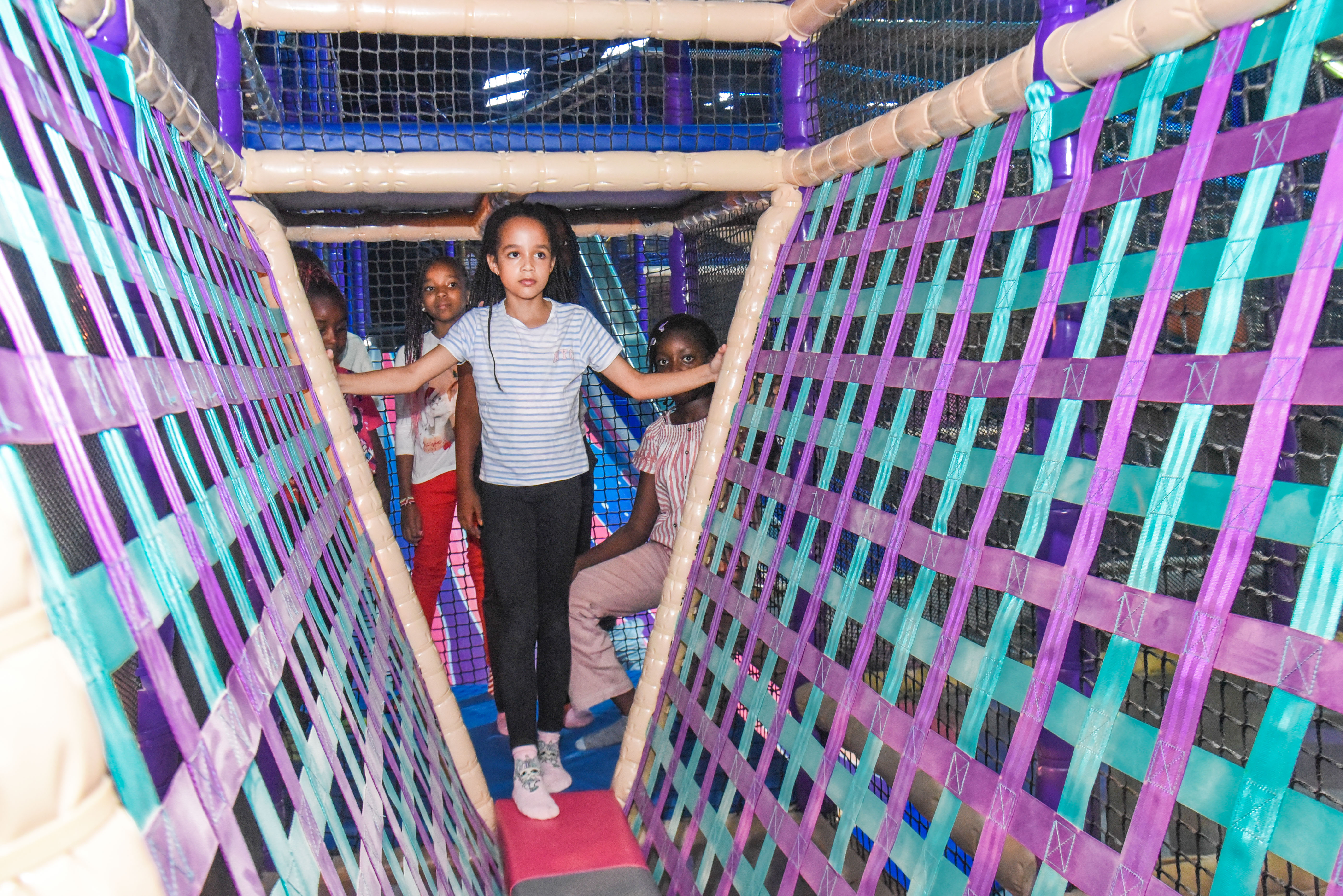 Child balancing in the net maze challenge at The Hub Park, a thrilling indoor fun zone and bounce place.