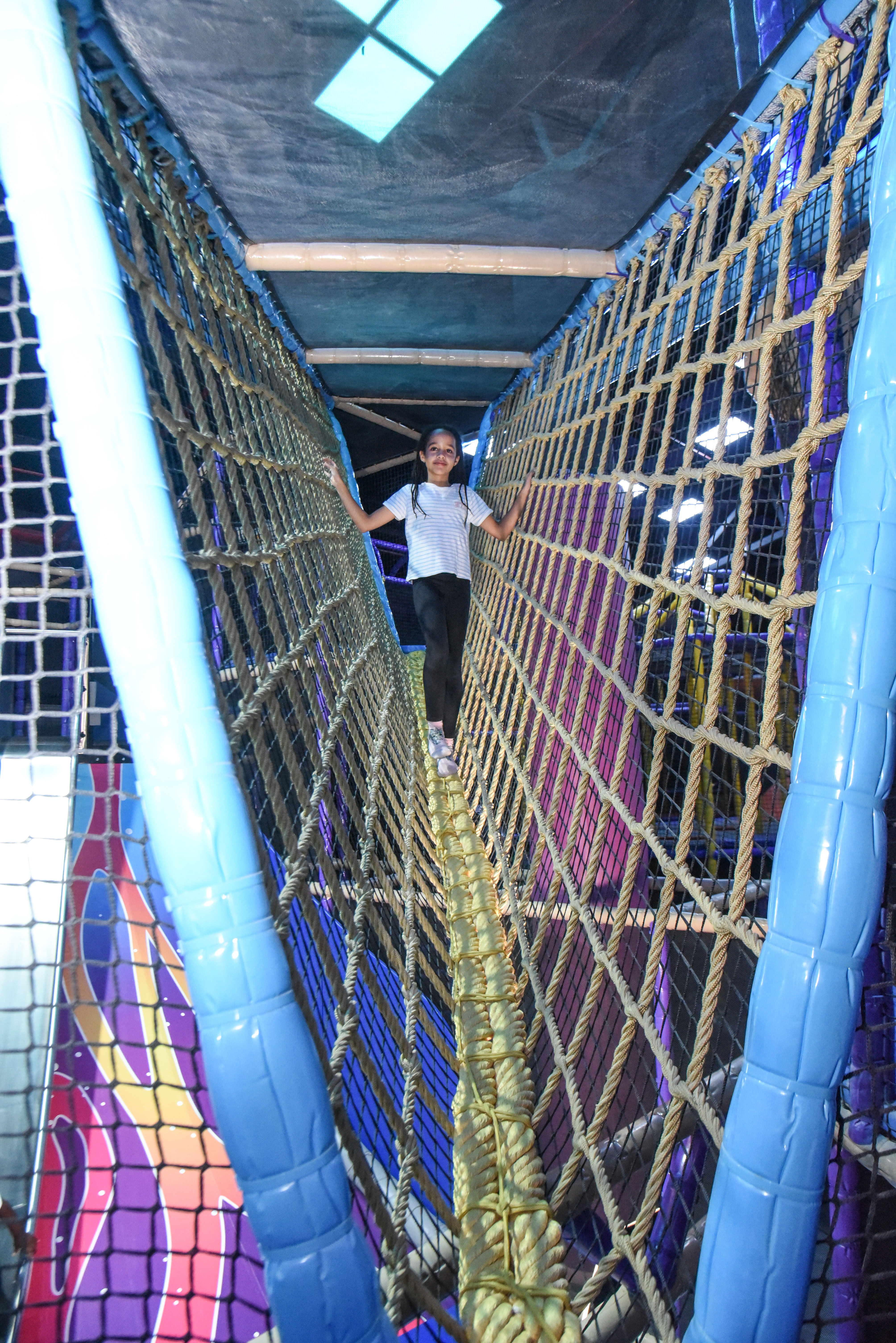 Child balancing in the net maze challenge at The Hub Park, a thrilling indoor fun zone and bounce place.
