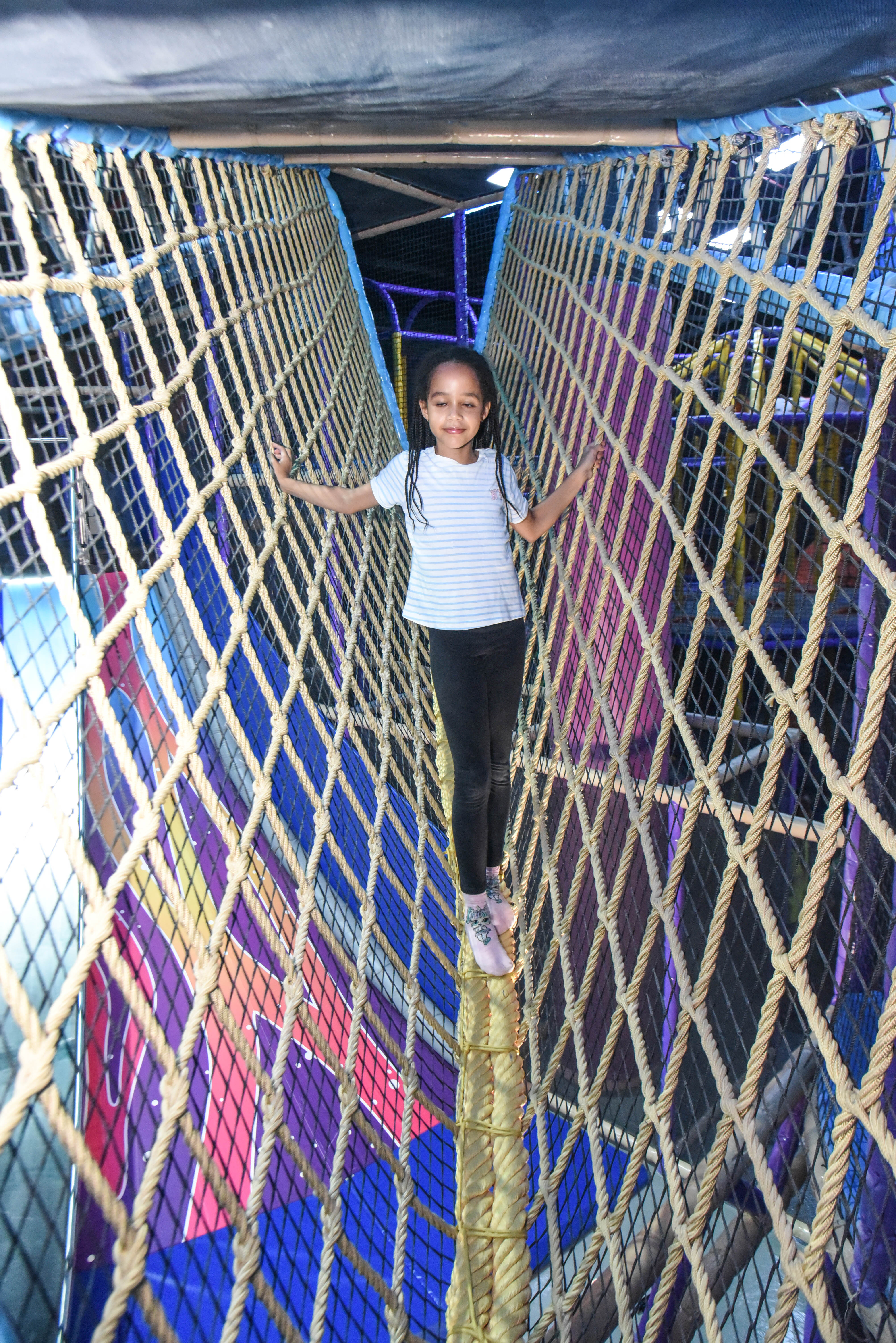 Child balancing in the net maze challenge at The Hub Park, a thrilling indoor fun zone and bounce place.
