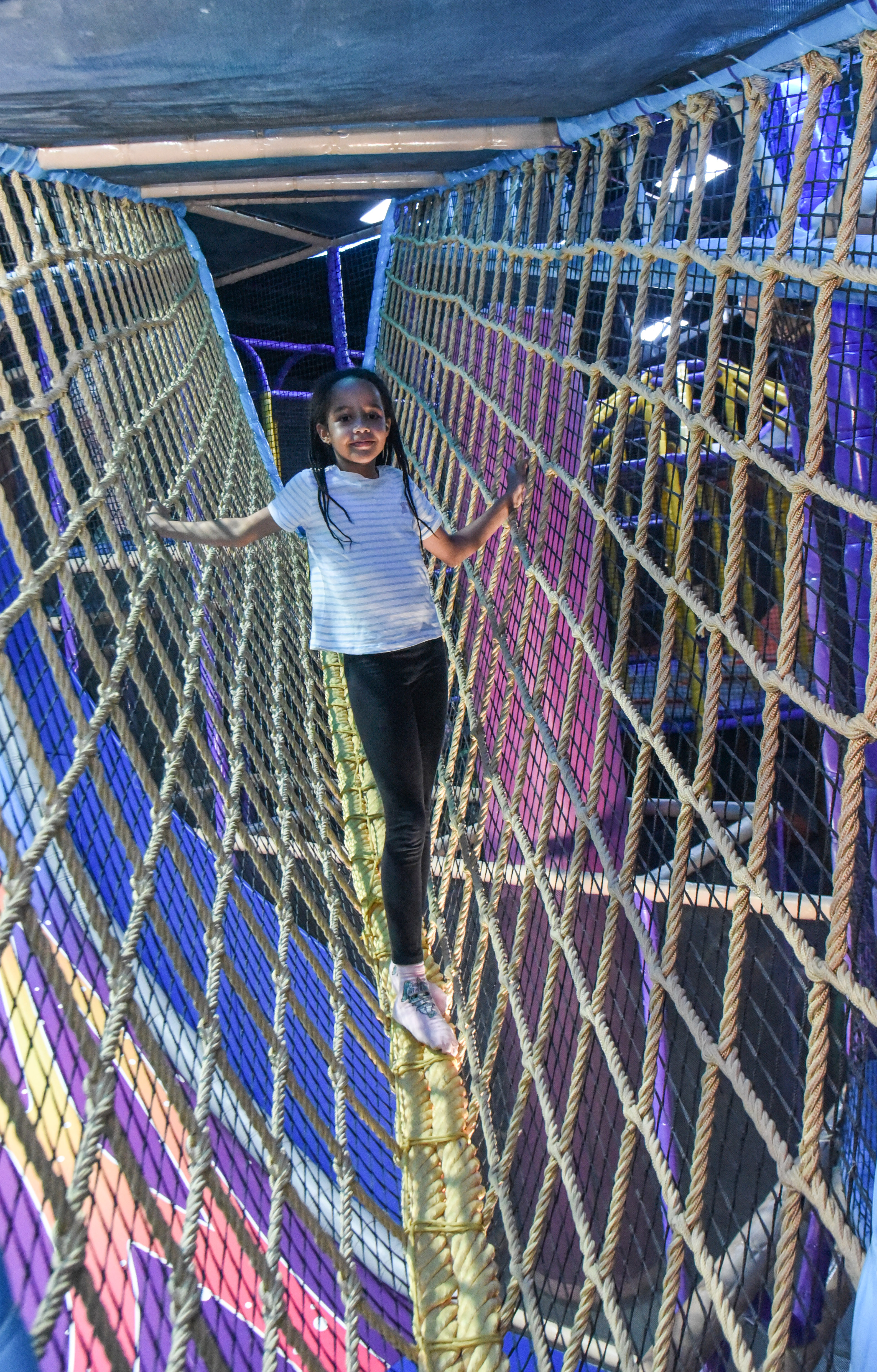 Child balancing in the net maze challenge at The Hub Park, a thrilling indoor fun zone and bounce place.